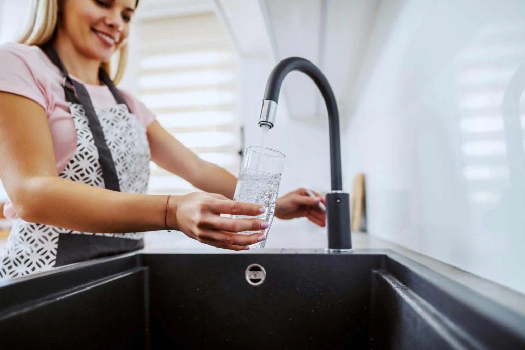 girl pouring water in glass from tap